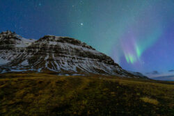 Faint aurora over grass fields and snow capped hill dsc 4453