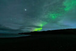 Green aurora between the clouds on black beach dsc 4572