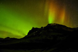 green arc aurora and red pillars over a mountainside newmohawk